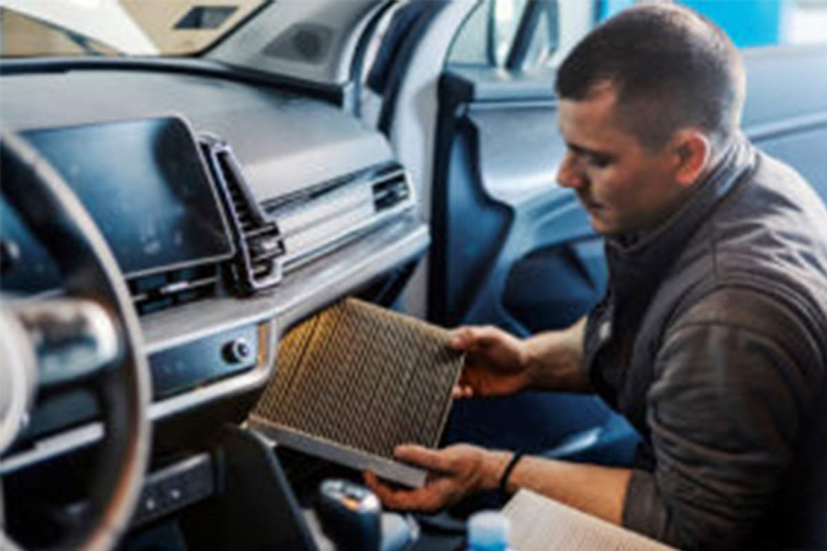 Ein Kfz Mechaniker wächselt einen Motorfilter