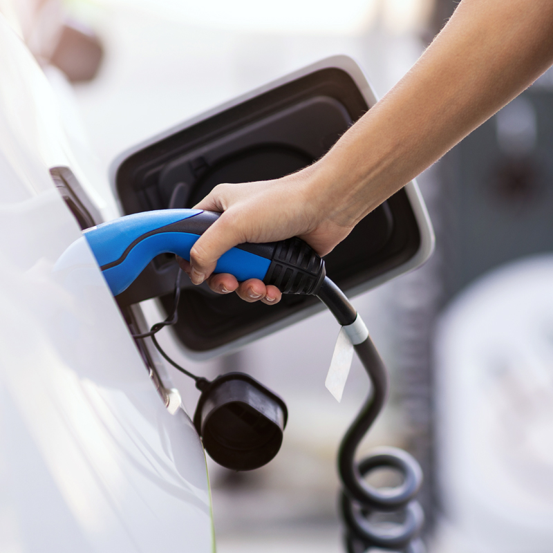 Bild zeigt eine Person, welche ihr Auto zum Laden anschließt